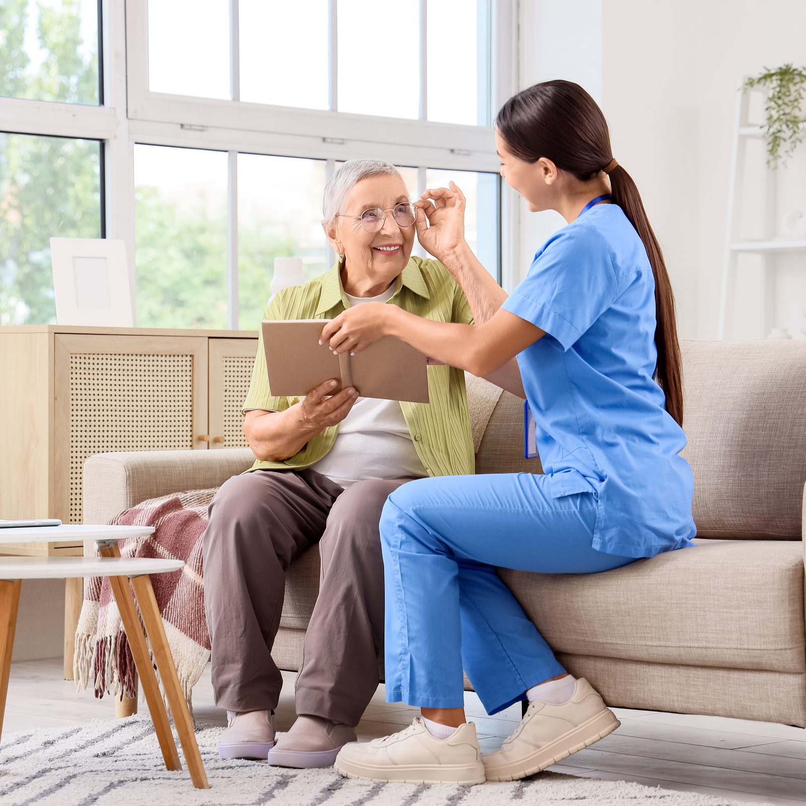 A caregiver and an older adult smiling together in a sunlit Oregon living room